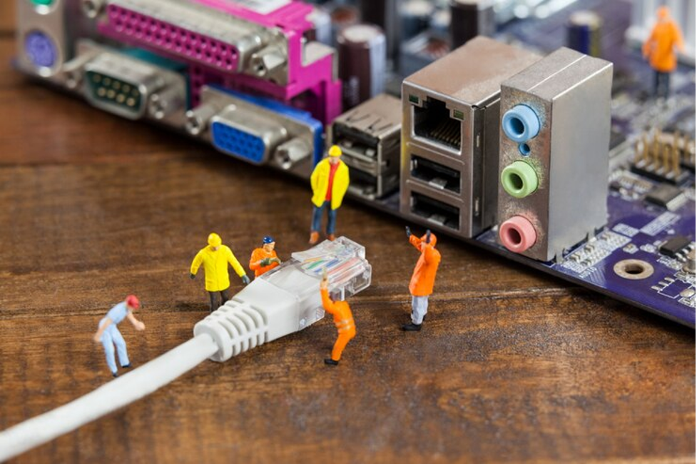 Sebuah kabel yang akan dimasukkan ke port, dengan patung kecil yang sedang bekerja di atasnya sebagai ilustrasi keuntungan jaringan komputer topologi bus.